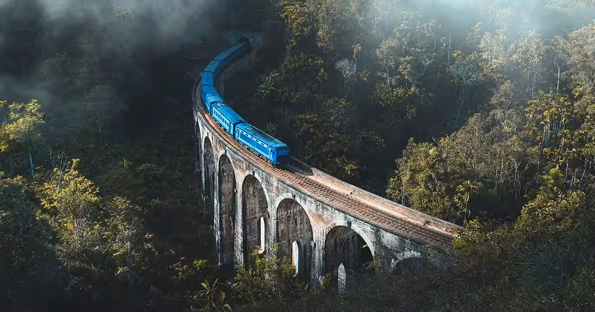 What to Do in Sri Lanka in October & November 10 Blue train crossing the Nine Arches Bridge in Ella surrounded by misty jungle